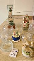 Overview of lot showing Peanuts snow globe, ceramic birds, musical Cardinals egg, glass vases, and rose under glass