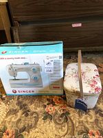 Singer Simple 2263 sewing machine boxed next to floral sewing basket on carpeted floor