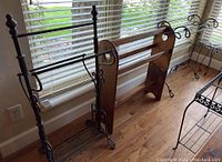 Photo showing two black metal quilt racks and one wooden rack placed on wooden floor by window