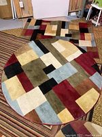 Four rugs with geometric squares pattern from Barclay Collection, including one round large rug and three rectangular/runners.