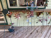 Photo of large metal garden ornaments including wind spinners, scarecrow, and butterflies displayed on a porch