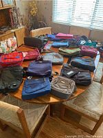 Overview of all purses spread on a round wooden table showing various colors and sizes