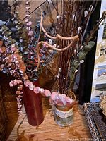 Close view of faux plant arrangements featuring eucalyptus, pussy willow, dried twigs in vases