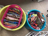 Two plastic storage bins with folded and loose fabric scraps in varied colors and patterns