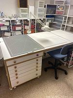 Front view of full sewing table assembly with cutting mat, lamp and chair