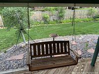 Wooden porch swing hanging by metal chains outdoors