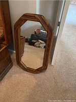 Wooden framed mirror with octagonal design, leaning against wall.