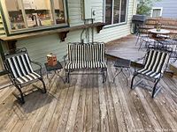 Front view of two chairs, loveseat, end tables and candle holder on wooden deck
