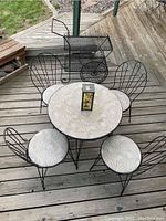 Top-down view of the wrought iron round table with four matching chairs and centerpiece lantern on wooden deck.