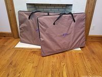 Two folded carrying cases for the crates laid upright on hardwood floor in front of a fireplace.