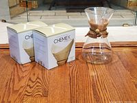 Chemex glass coffee maker with two unopened boxes of Chemex brand natural paper filters