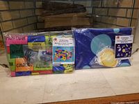 Two packaged felt wall hangings, one with a colorful United States map showing state names and the other with a depiction of the Solar System on a dark blue background.