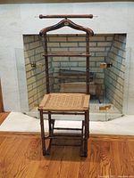 Front view of mid-century folding valet chair with woven seat, brass accents, and walnut frame