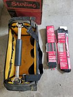Portable tool bag with two sets of screwdriver bits in red packaging