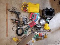Overview of assorted tools, cords, boxes, hardware and supplies laid out on floor showing variety of items in lot.