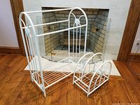 Wide photo showing both the larger towel rack and smaller accessory rack side by side on a wooden floor in front of a fireplace.