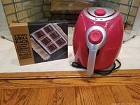 Photo showing the S'mores Grill Rack boxed and the red air fryer side by side.
