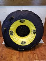 Front view of inflated towable tube with black and yellow color scheme showing brand logos and four handles.