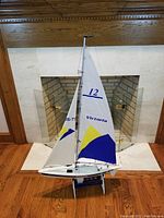 Full view of Victoria R/C sailboat showing sail, rigging, and stand in front of fireplace.