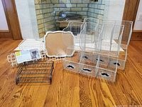 Photo showing all items including four white wire wall-mounted bins with moustache cutouts, cork board with scalloped edges, and smaller wire organizers on hardwood floor.
