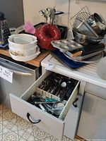 Kitchen drawer open showing stainless steel cutlery and various kitchen utensils