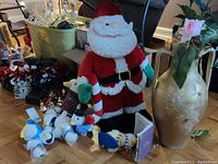 Photo showing large plush Santa, several Aflac duck plush toys in costumes, a 21-inch tall gold vase with faux flowers, and some wreaths on the floor.