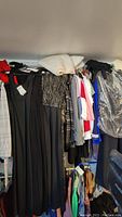 Photo showing black maxi dresses, tops, and outerwear arranged on clothing rack, some items draped and others on hangers