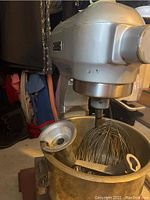 Front angle showing mixer head, bowl, whisk, flat beater and funnel-like attachment inside bowl