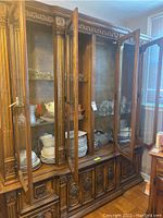 Glass-front wood cabinet displaying the sets of plates, bowls, and glassware inside.
