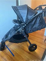 Side view of black Baby Jogger City Mini GT stroller showing collapsible hood and cup holder on handlebar