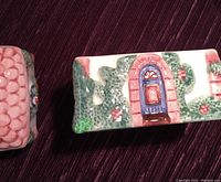 Top view of salt and pepper shakers showing colorful village house design with textured pink roof and blue doors. Visible surface crazing on salt shaker roof.