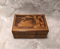 Top view of wooden box showing detailed swan and bamboo inlay on lid with polished wood grain surface.