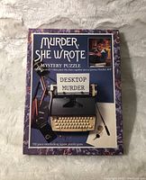 Full front view of the Murder She Wrote Desktop Murder puzzle box showing typewriter and title.