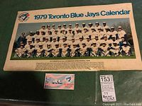 Full team photo calendar poster and first game ticket displayed on green surface.