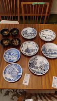 Photo showing all 10 items including black and gold floral bowls and blue and white winter scene plates arranged on a wooden table.