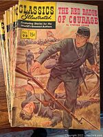 Stack of 21 Classics Illustrated comic books shown from the front cover, The Red Badge of Courage as the featured cover with a soldier in blue uniform and a rifle, priced at 15 cents.