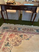 Front view of the wooden console table with two drawers and cabriole legs.