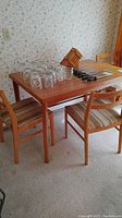 Wooden dinette table with three chairs around it, glasses and knives on table surface