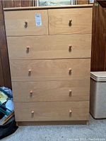 Front view of IKEA 6 drawer dresser with light wood finish and wooden knobs on each drawer.
