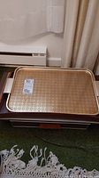 Gold metal hot plate serving tray with detailed pattern, shown on top of other trays