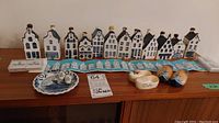 Full view of lot including 10 miniature Dutch houses, ceramic clogs, decorative plate, tiles, and poster