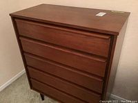 Full front view of five-drawer dresser showing recessed pull rails and tapered legs