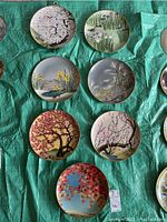 Top view of all seven decorative plates arranged showing variety of floral and tree designs in colorful detail