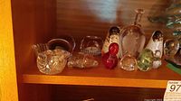 Shelved crystal and glass figurines including various birds, a red animal-shaped piece, and clear glass shapes.