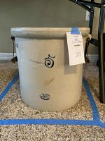 Front view of crock showing cobalt blue spiral decoration, maker’s stamp, and attached tag