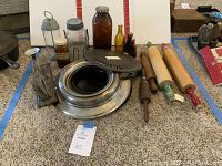 Photo showing full assortment of antique glass bottles, wooden rolling pins, metal bakeware pans, cast iron skillet and vintage kitchen utensils on carpeted floor.