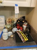Overview of assorted Asian inspired decor items including teapots, cups, fans, and figurines placed on kitchen countertop.