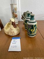 Photo showing three vases (including floral and iridescent) behind the ceramic duck planter on a table