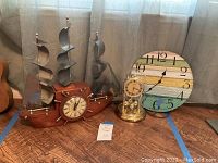 Three clocks in total: ship-shaped clock with sails, golden glass anniversary clock, and round wooden beach-themed wall clock