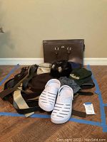 Full lot showing leather laptop bag, multiple belts, various hats, and white Nautica crocs
